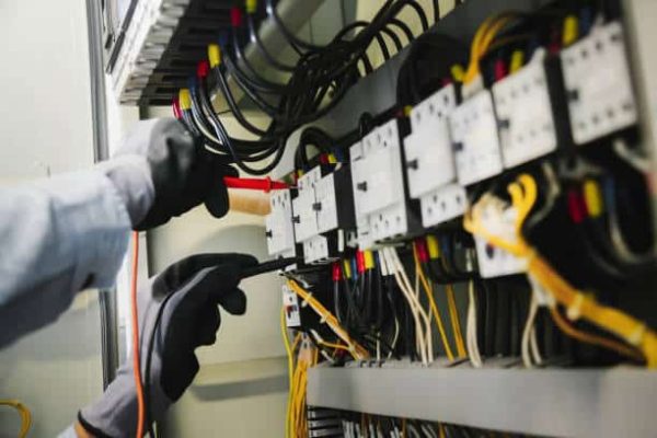 Electrical engineers test electrical installations and wiring on protective relays, measuring them with a multimeter.